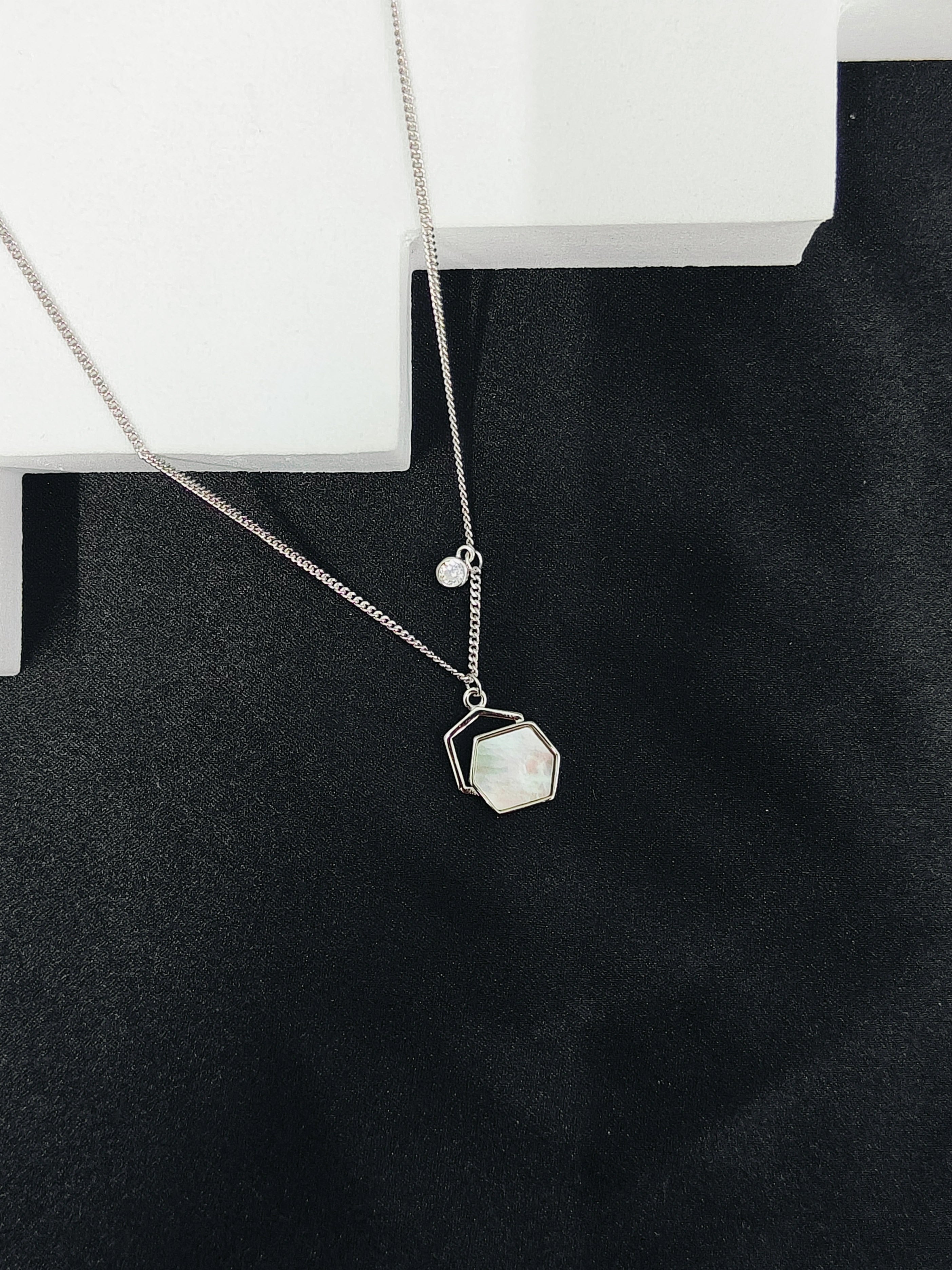 Necklace with a geometric pendant on a black surface